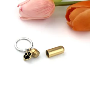 Close-up detail of gold pet urn keychain showing open cylindrical memorial container
