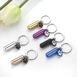 Detail view of six alloy cylindrical pet cremation urn keychains with paw print charms.