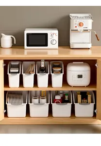 Minimalist white kitchen storage bins with grey handles organized inside a wooden cabinet