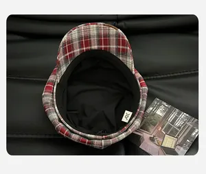 Close-up detail showing the black inner lining and brand tag of a red plaid beret