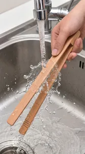 Action shot of durable beech wood kitchen tongs being rinsed under a running water faucet