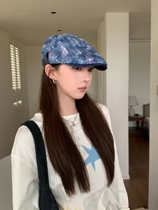 Détail d'un béret vintage en denim délavé avec des motifs d'étoiles blanches sur un mannequin