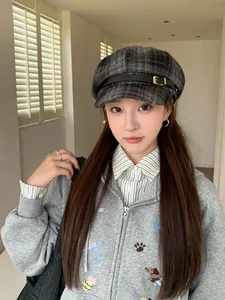Detailed shot of a vintage grey plaid octagonal newsboy hat with buckle on a model