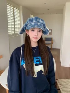 Model wearing a cute blue plaid octagonal hat with plush bunny ears in a bright room