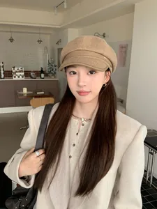 Stylish Asian model wearing a vintage wool newsboy cap with leather brim in a cozy cafe.