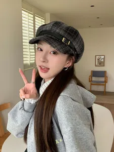 Close-up of a grey plaid baker boy hat with a black leather buckle strap on an Asian model
