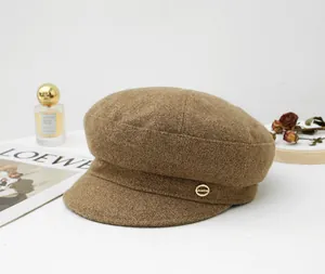 Detailed view of a stylish brown wool newsboy hat with a golden metal emblem accent