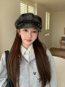 Close-up of a stylish vintage plaid newsboy hat worn by a female model in an indoor setting
