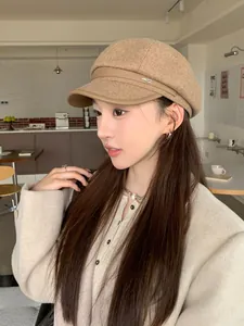 Side view of a vintage camel woolen newsboy hat with a leather brim on a model