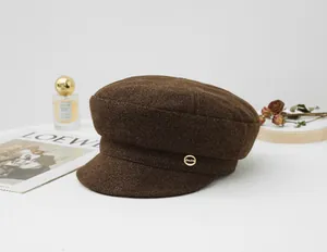Brown wool newsboy cap with gold accent on a white background with vintage props