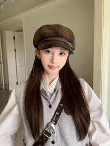 Close-up of a stylish women's brown plaid newsboy cap featuring a decorative leather strap detail