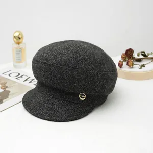 Detailed view of dark grey wool newsboy cap featuring a vintage gold side button accent