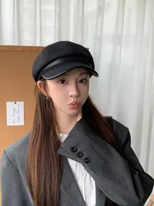 Stylish black wool newsboy baker boy hat with leather brim detail worn by a model