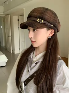 Close-up side view of a vintage brown plaid newsboy hat featuring a leather buckle strap