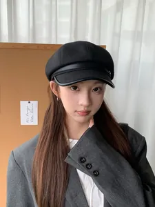 Asian model wearing a classic black wool newsboy cap with a stylish leather brim detail.