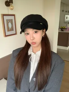 Elegant black wool newsboy hat with a leather brim worn by an Asian model in a room.