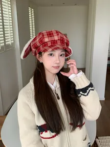 Sweet red plaid newsboy hat with plush bunny ears shown on model in cozy interior
