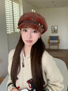 Detailed view of a retro orange plaid newsboy cap with leather buckle on a model