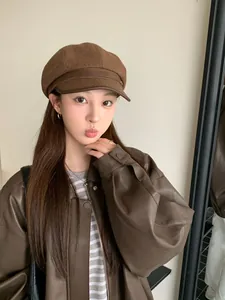Vintage brown wool newsboy cap with leather brim detail worn by a model in soft light