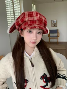 Close-up detail of a red plaid newsboy cap featuring plush white rabbit ears on a model