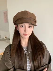 Close-up of a vintage brown wool newsboy hat with a stylish leather brim worn by a model.