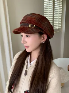 Side view of a woman wearing a vintage brown plaid newsboy hat with leather buckle.