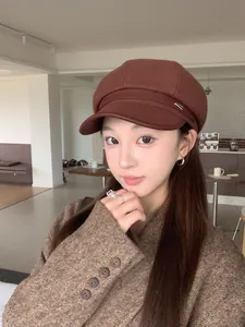 Vintage brown woolen newsboy hat with leather brim worn by a model in a cafe