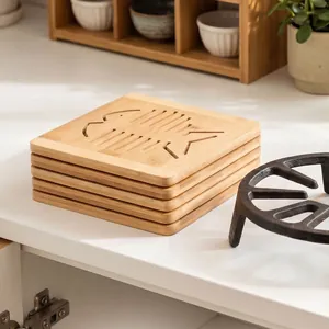 Stack of bamboo heat-insulating mats with hollow fish skeleton pattern on white table