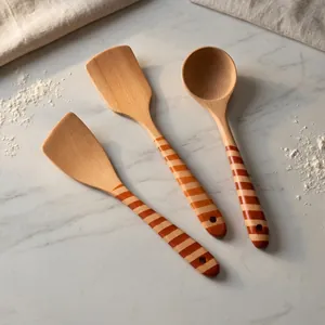 Juego de espátulas y cucharas de madera de haya con mangos a rayas sobre mármol.