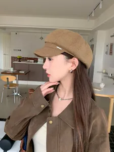 Close-up detail of a retro brown newsboy cap worn by a model in a cozy cafe setting