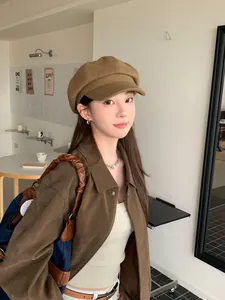 Model wearing a vintage brown octagonal baker boy hat in a minimalist cafe setting