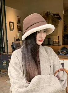 Model wearing a stylish brown wool bucket hat with a plush white furry brim for winter.