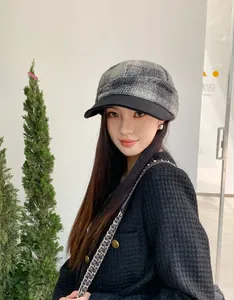 Close-up of a model wearing a grey plaid wool newsboy hat for autumn and winter