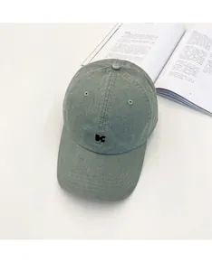 Detailansicht einer gewaschenen salbeigrünen Kinder-Baseballkappe mit schwarzem Logo.