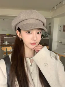 Close-up of a stylish retro beige newsboy hat worn by an Asian model in a cozy cafe setting
