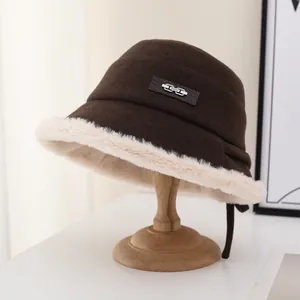 Detail view of a brown wool bucket hat with thick cream fur trim and brand patch
