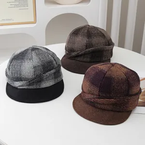 Vintage plaid wool newsboy caps in gray and brown tones displayed on a white table