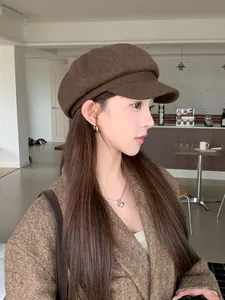 Close-up of a woman wearing a vintage brown baker boy hat in a stylish cafe setting