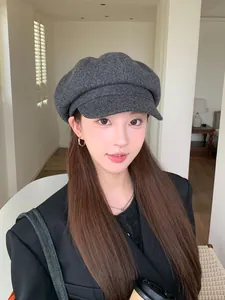 Close-up of a stylish dark grey wool-textured newsboy hat worn by a young woman