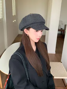 Close-up of a dark grey wool newsboy hat on a woman, showing fabric texture and style