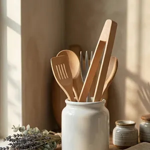 Minimalist natural beech wood kitchen tongs and utensils set displayed in a white ceramic jar.