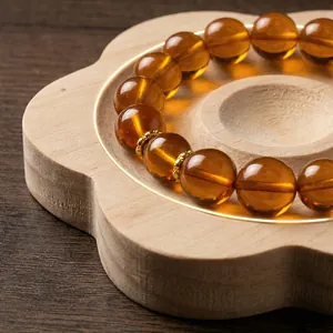 Flower-shaped wooden jewelry display tray for amber bead bracelets.