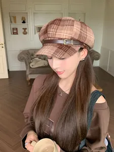 Close-up of an Asian model wearing a brown plaid newsboy hat with a leather strap
