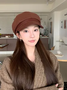 Close-up view of a vintage brown wool newsboy hat with a leather strap on a model