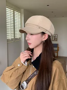 Elegant beige wool newsboy hat with leather brim, stylishly worn by model in profile