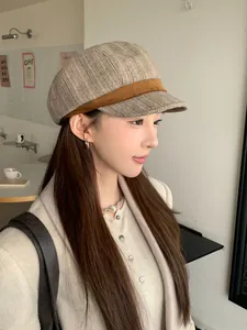 Stylish woman wearing a brown herringbone newsboy cap, side view in cafe setting