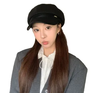 Stylish black wool newsboy hat with faux leather brim detail worn by a fashion model