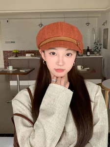 Stylish orange newsboy cap shown on an Asian model in a cozy cafe setting