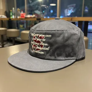 Detailed view of white cursive embroidery and red letter S on gray flat brim cap
