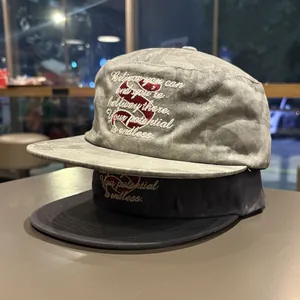 Close-up of stacked cotton flat-brimmed caps with inspirational embroidered text for couples.
